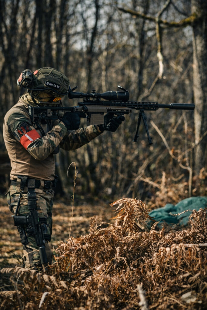 Joueur d’airsoft équipé en tireur de précision lors d’une partie milsim en forêt en Dordogne.