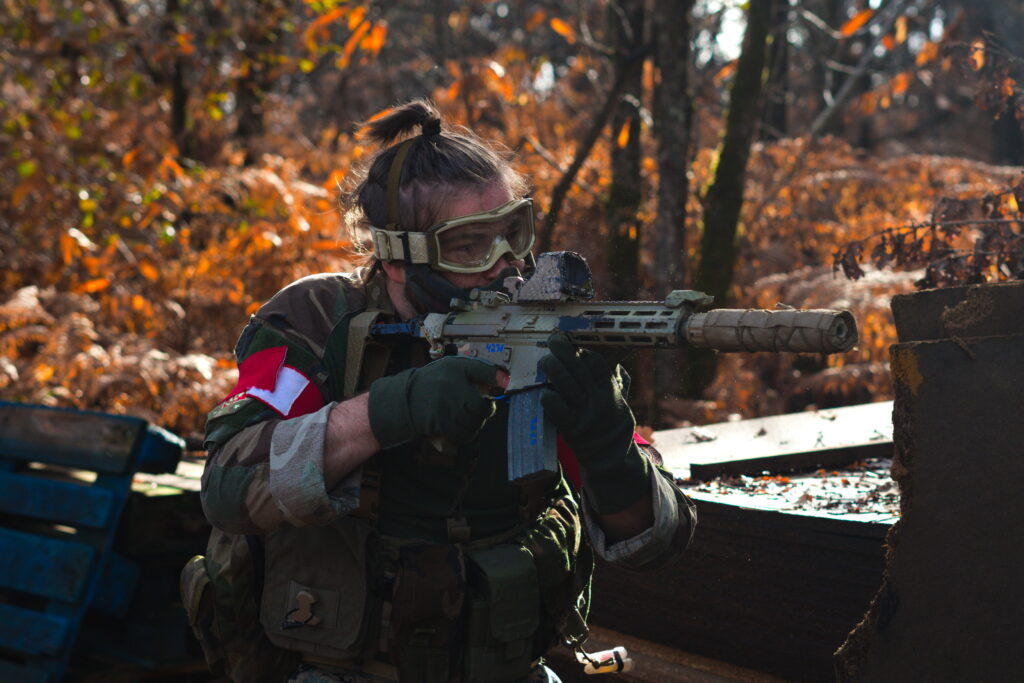 Joueur d’airsoft en tenue tactique participant à une simulation militaire en forêt en Dordogne.