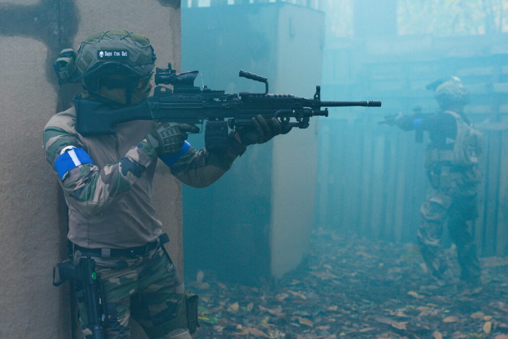 Joueur d’airsoft progressant sous un écran de fumigène lors d’un scénario tactique immersif en Dordogne.