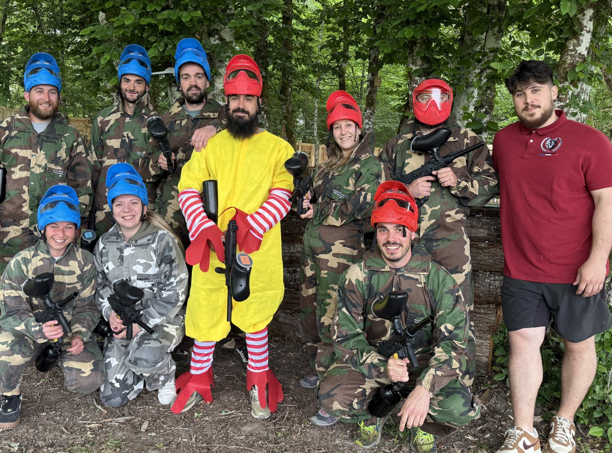 Groupe de joueurs de paintball en Dordogne posant avec un participant déguisé lors d’un enterrement de vie de garçon.