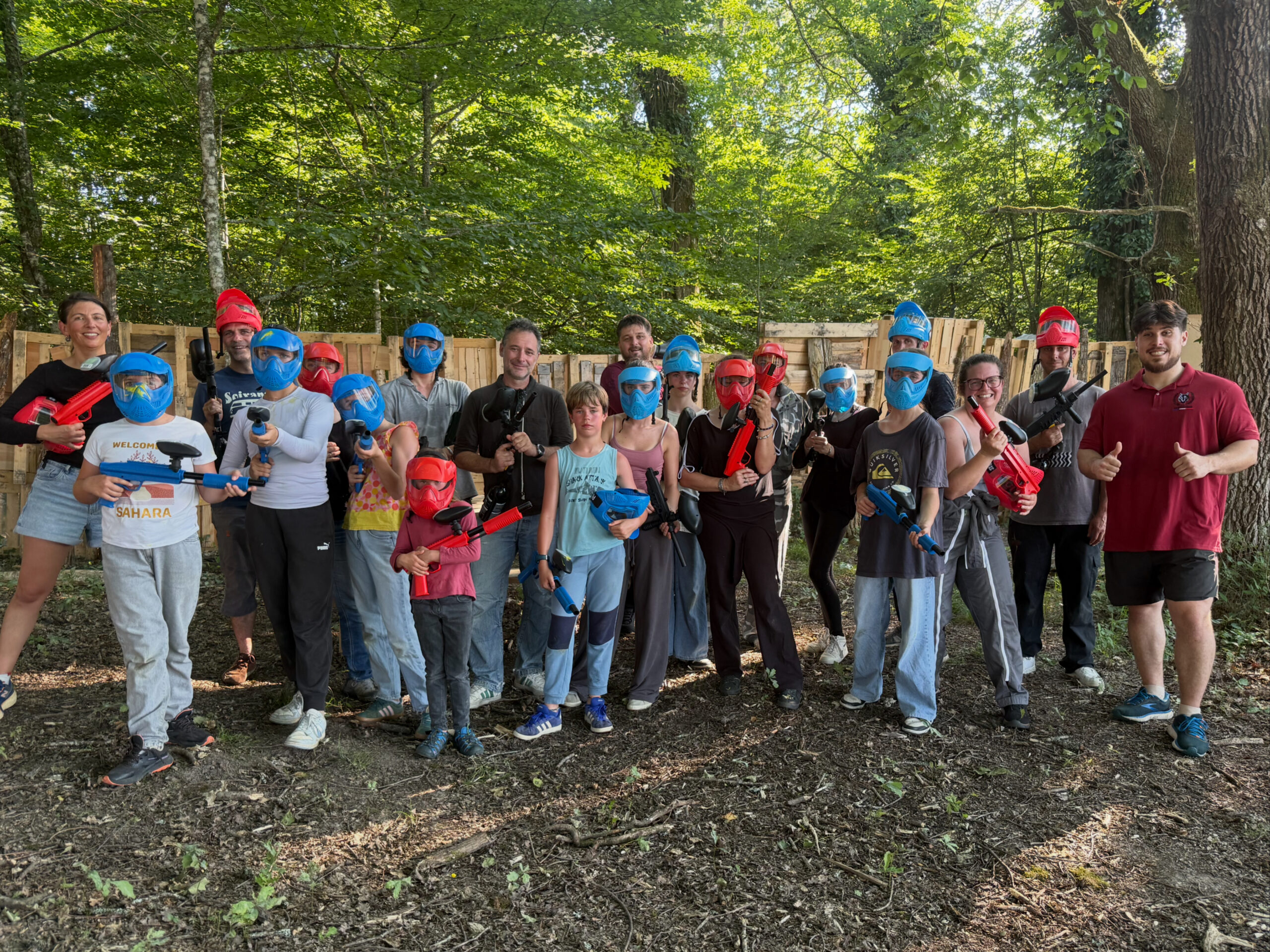 Famille et groupe d’amis réunis après une partie de paintball en forêt en Dordogne.