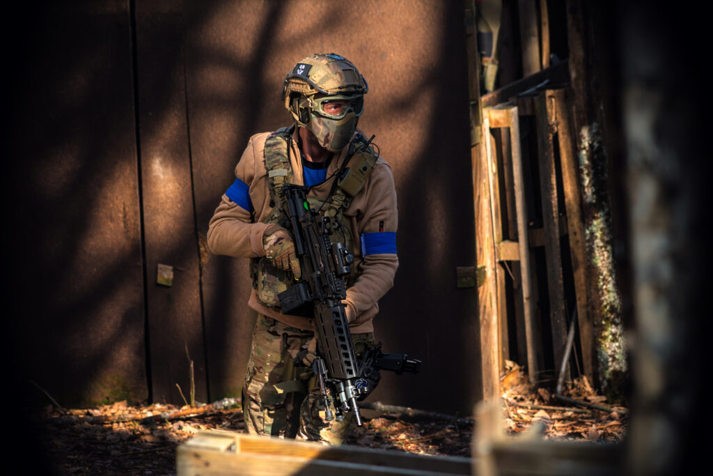 Joueur d’airsoft en équipement tactique progressant dans une zone de combat scénarisée sur le terrain La Confrérie en Dordogne